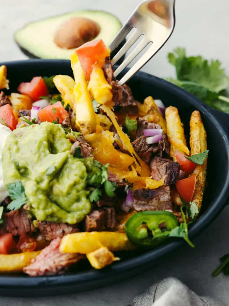 Close-up of carne asada fries being stuck with a fork.