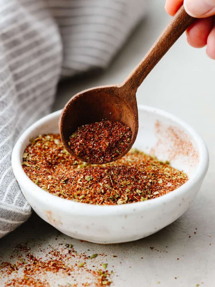 Herbs and spices mixed together to make chili seasoning in a small white bowl.