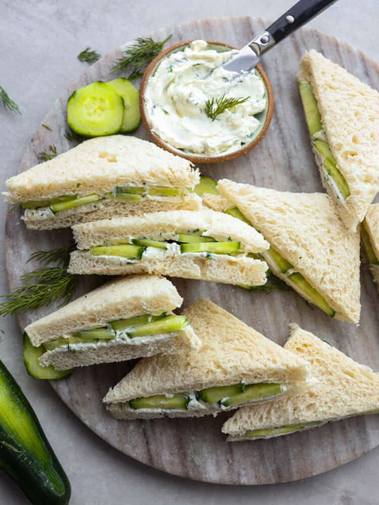 Top-down view of sliced cucumber sandwiches served with lemon dill spread.