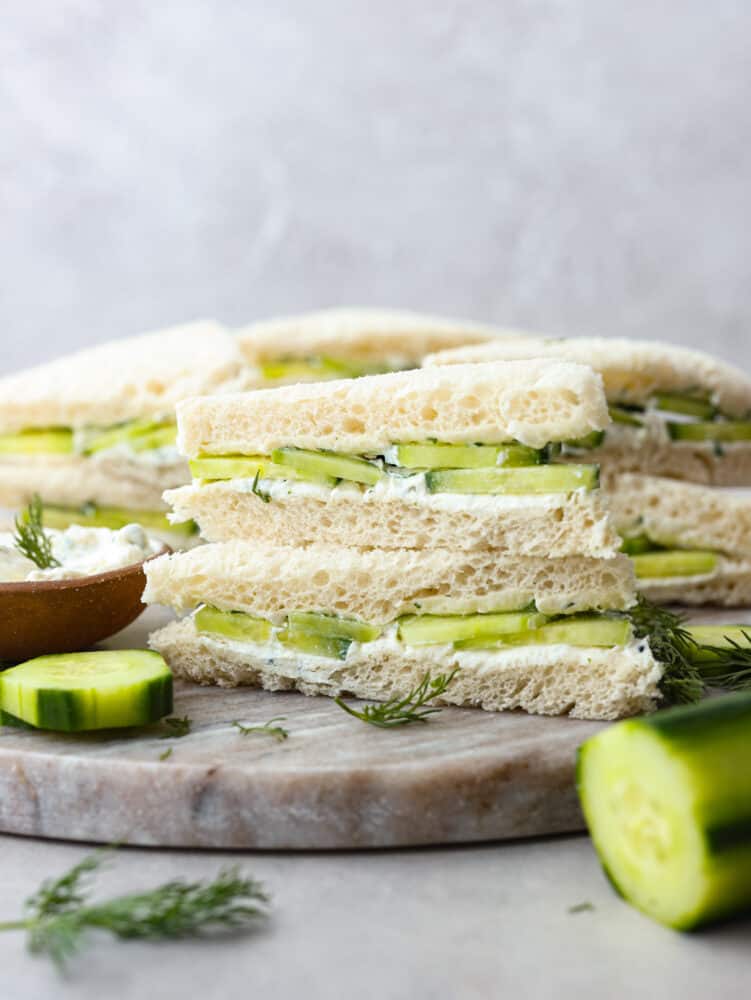 Cool and crisp, cucumber sandwiches are the perfect summer appetizer! Each sandwich is lined with a creamy lemon herb spread for a pop of zesty flavor. You'll love them! A stack of 2 cucumber sandwiches.
