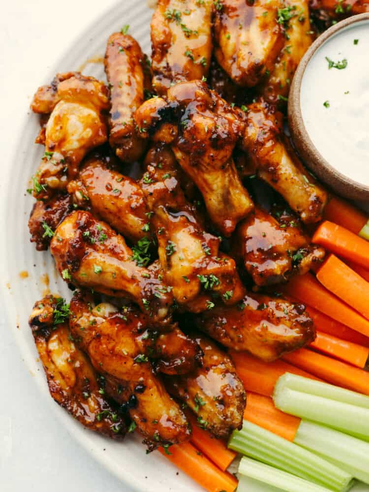 Top-down view of chicken wings served with dipping sauce and fresh vegetables.