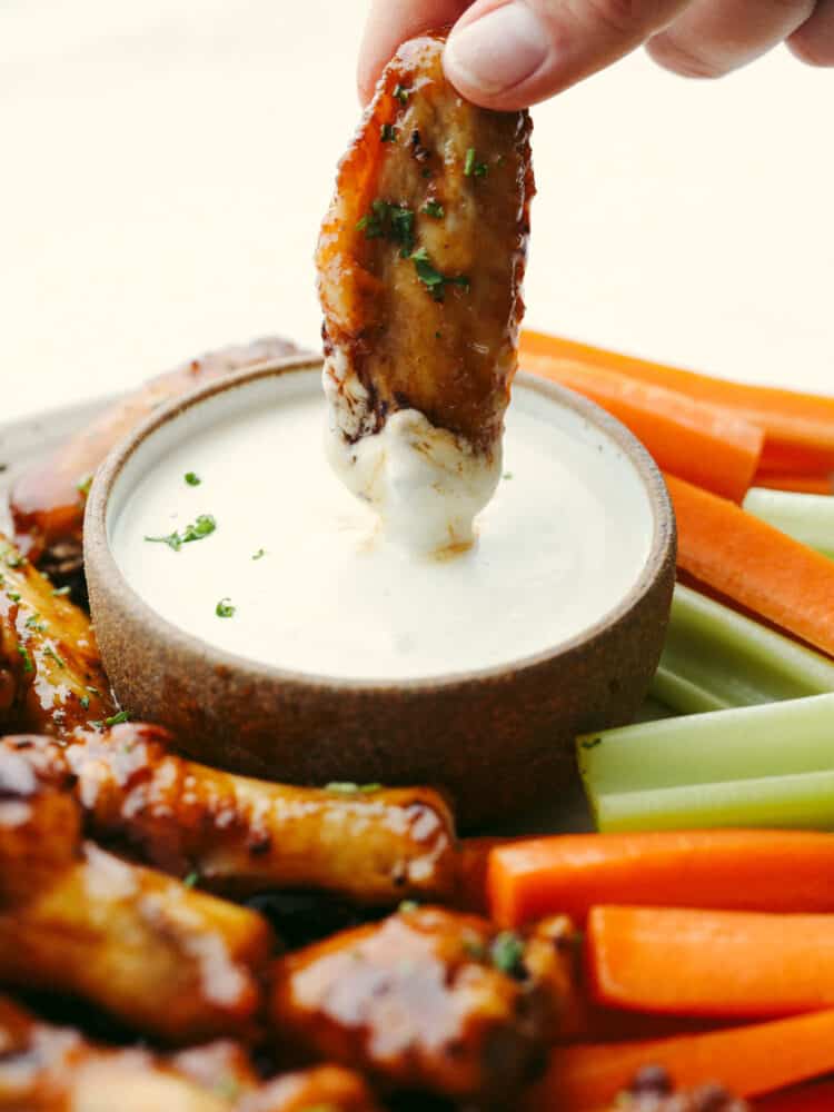 Dipping a chicken wing in a creamy sauce.