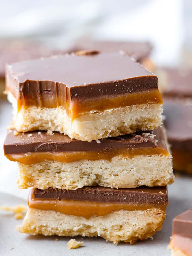 A stack of homemade Twix bars, the top one has a bite taken out of it. 