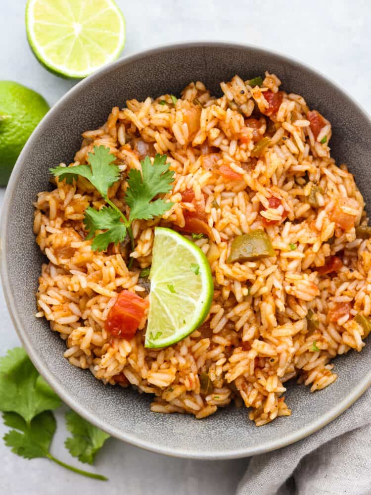 A bowl of Mexican rice garnished with cilantro and a slice of lime. 