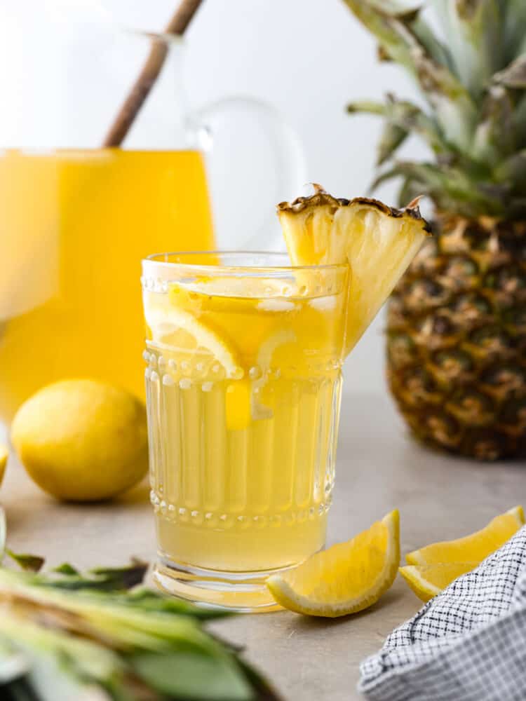Lemonade in a small glass cup, garnished with a slice of pineapple.