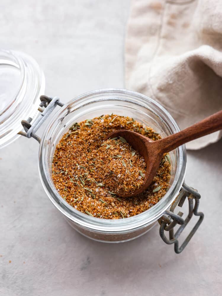Pork seasoning in a small jar with a wooden spoon. 