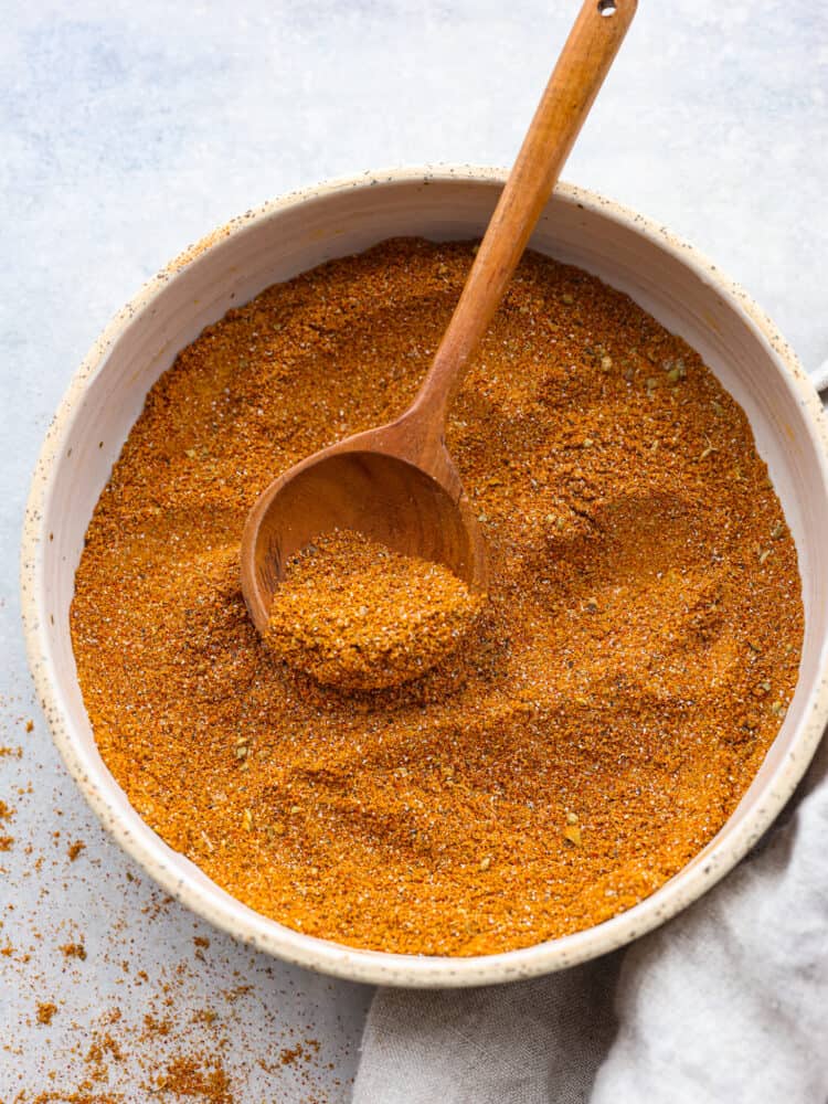 A bowl of mixed spices with a wooden spoon. 