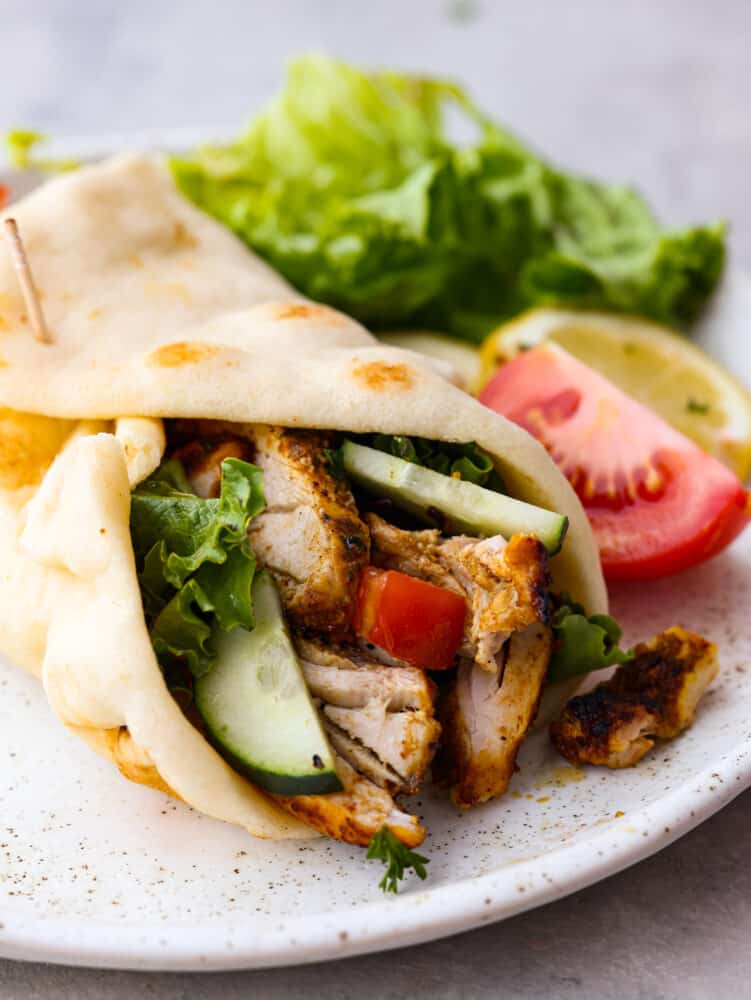 Chicken shawarma wrapped in a pita with some vegetables. 