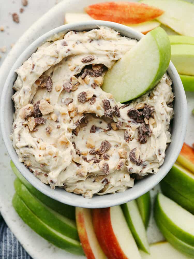 An apple slice in a bowl of toffee apple dip. 