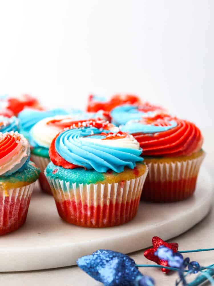 Red, white and blue cupcakes on a marble cutting board. 