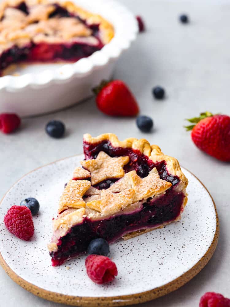 A slice of triple berry pie on a stoneware plate.
