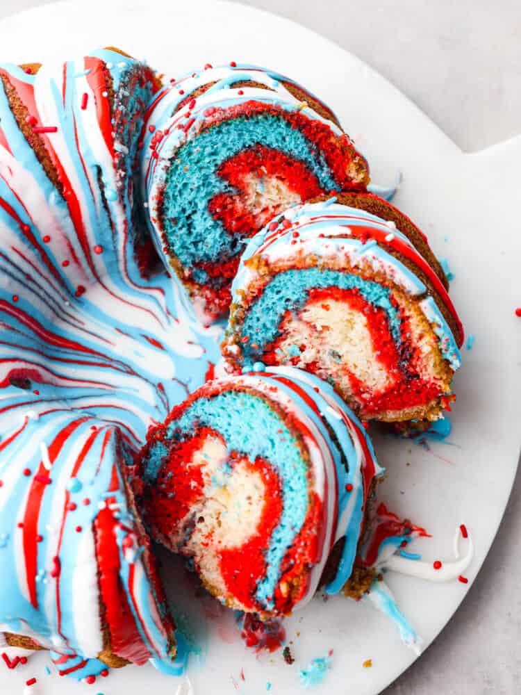 The top view of a firework bundt cake with a few pieces slices so that you can see the marbles red white and blue inside. 