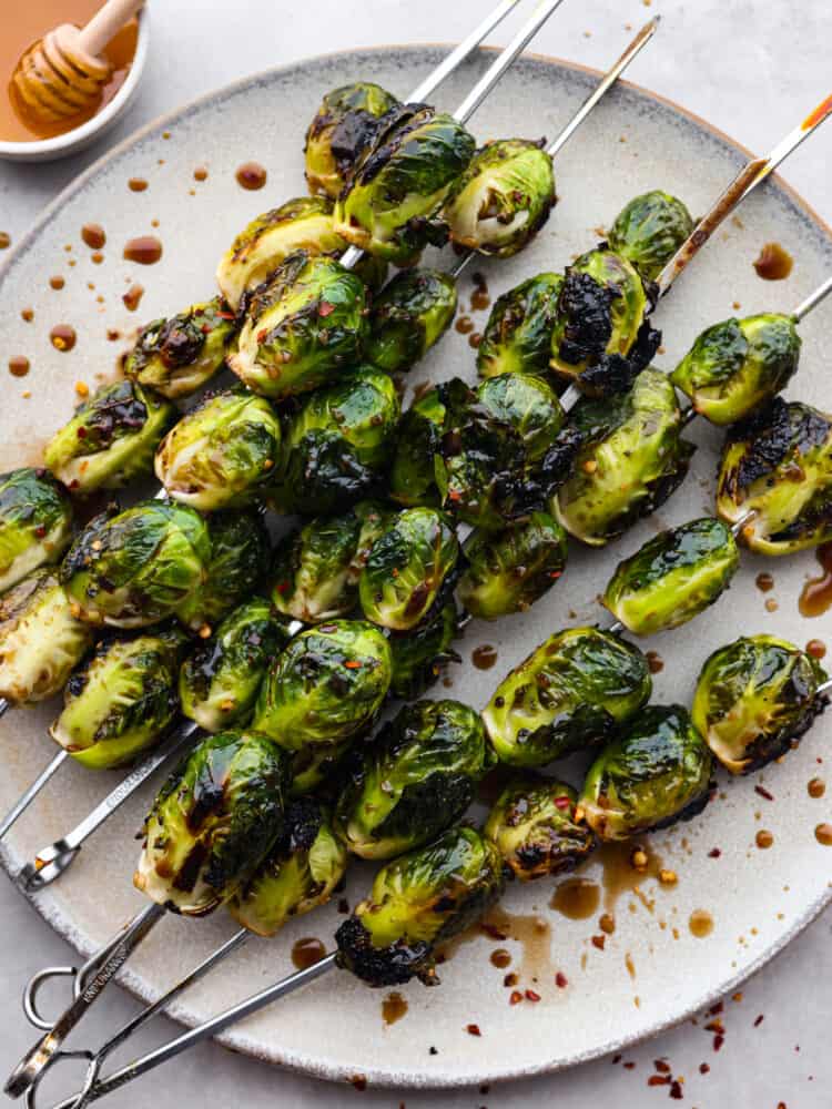 Top-down view of grilled brussels sprouts on a gray stoneware plate.