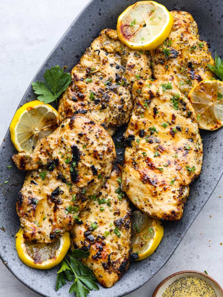 The top view of grilled lemon pepper chicken on a gray platter. 