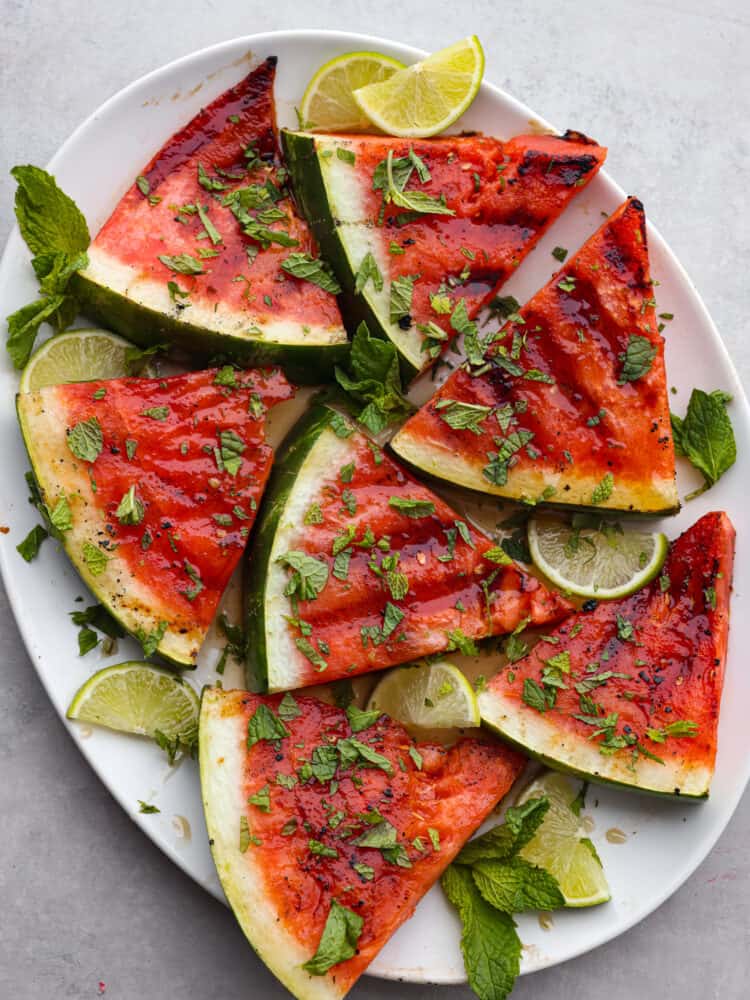 Top-down view of sliced, grilled watermelon on a white plate.