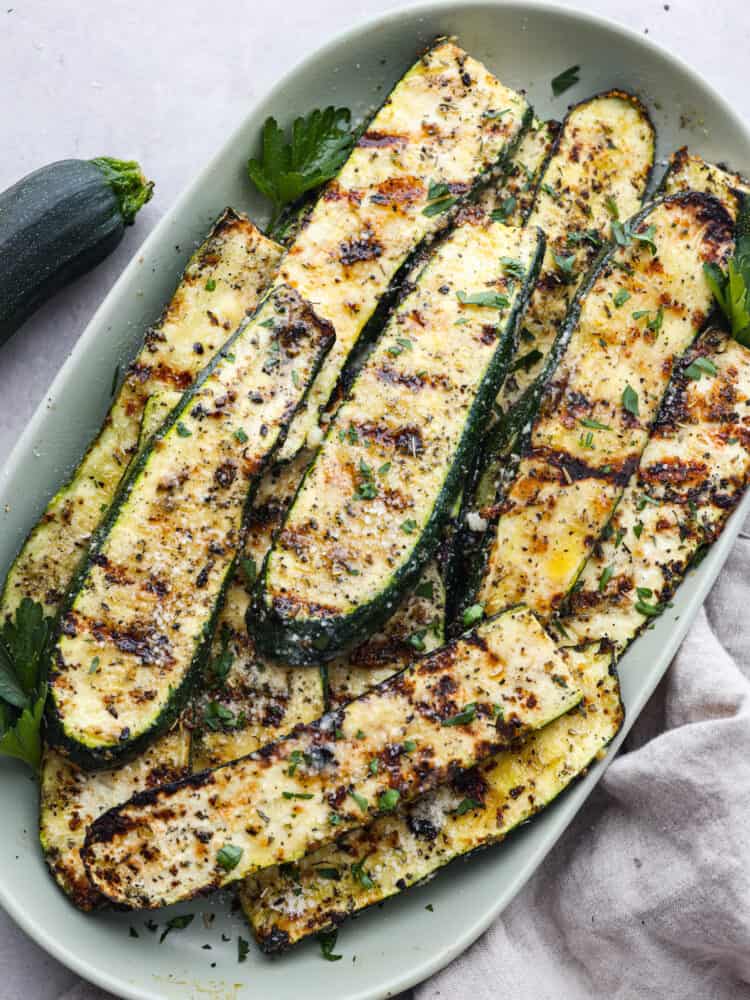 Slice, grilled zucchini seasoned and ready to eat in a white bowl. 