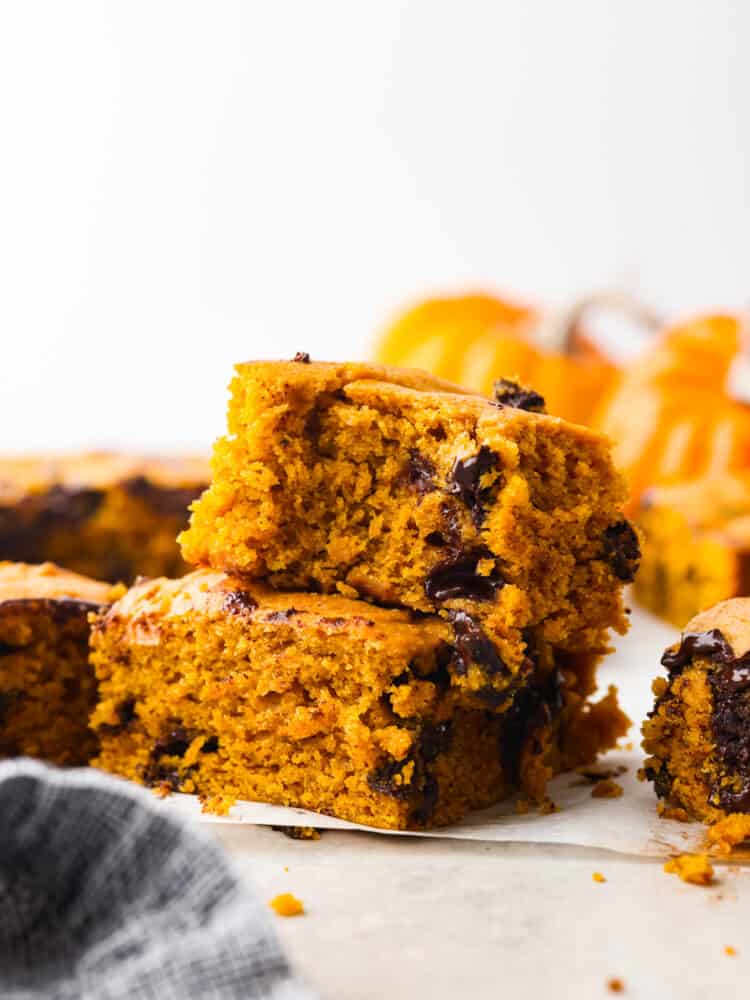 A stack of two pumpkin chocolate chip bars with a bite taken out of the top one. 