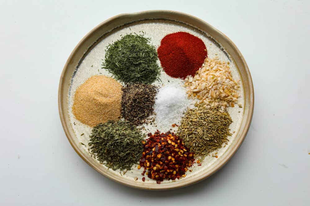 A bowl filled with seasonings and herbs measured out and ready to mix. 