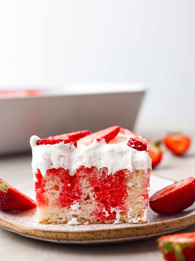 The side view of a slice of poke cake on a plate. 