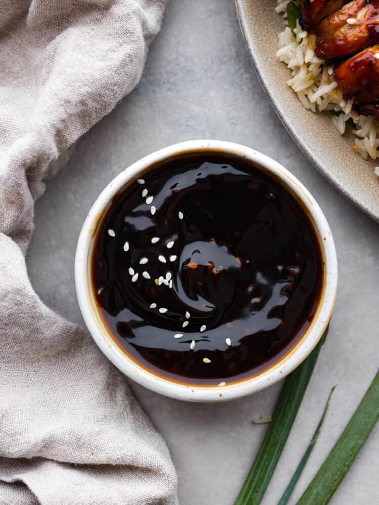 Yakitori sauce in a white bowl, garnished with sesame seeds.