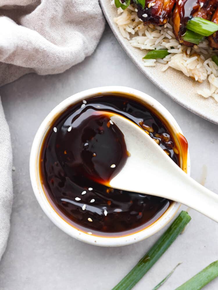 Top-down view of yakitori sauce in a white bowl, being stirred with a spoon.