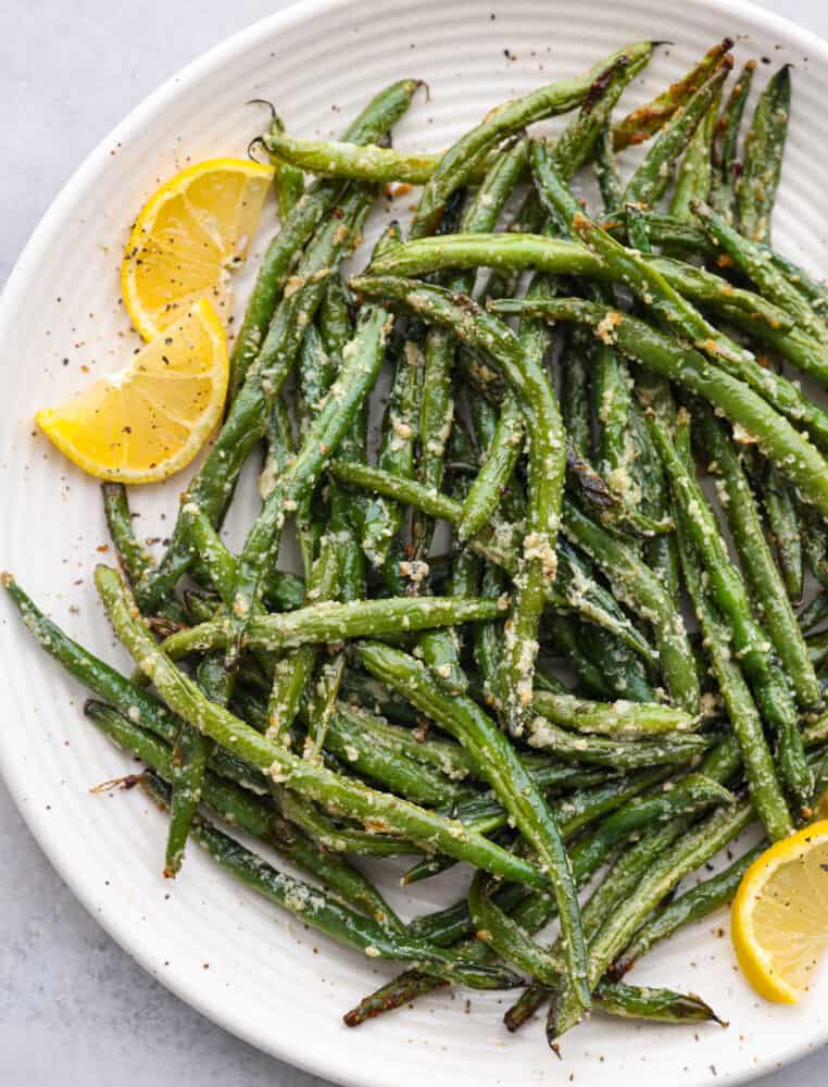 A plate with cooked and seasoned green beans. 