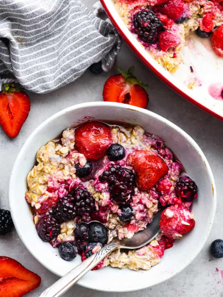 Cooked oatmeal in a white bowl, garnished with berries and ready to eat.
