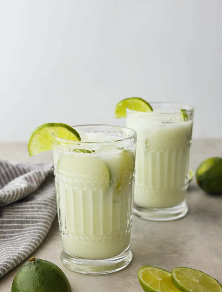2 glasses of limeade topped with lime slices.