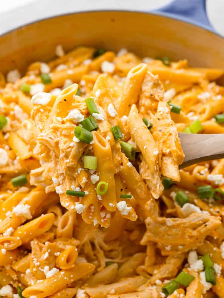 A closeup of a spoonful of buffalo chicken pasta on a wooden spoon. 