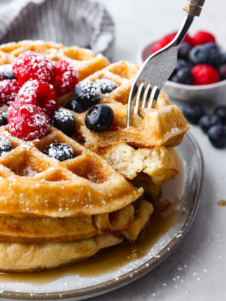 Closeup of a stack of 3 waffles, topped with berries.