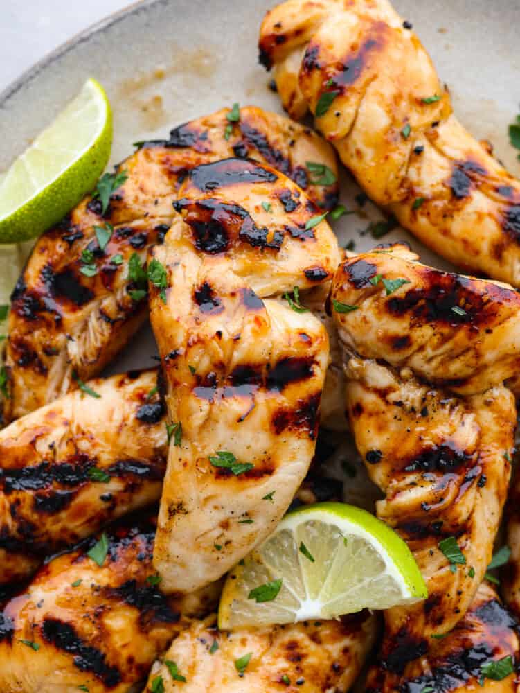 Closeup of chicken tenders garnished with chopped herbs and a lime slice.