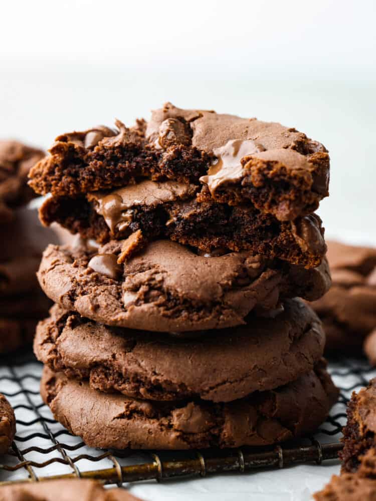 A stack of four chocolate cake mix cookies. The top one is broken in half so that you can see the soft, chocolate insides. 