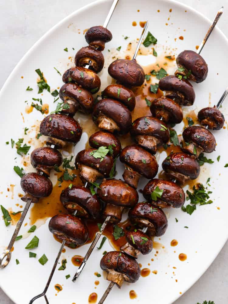 A platter with mushroom skewers cooked and garnished. 