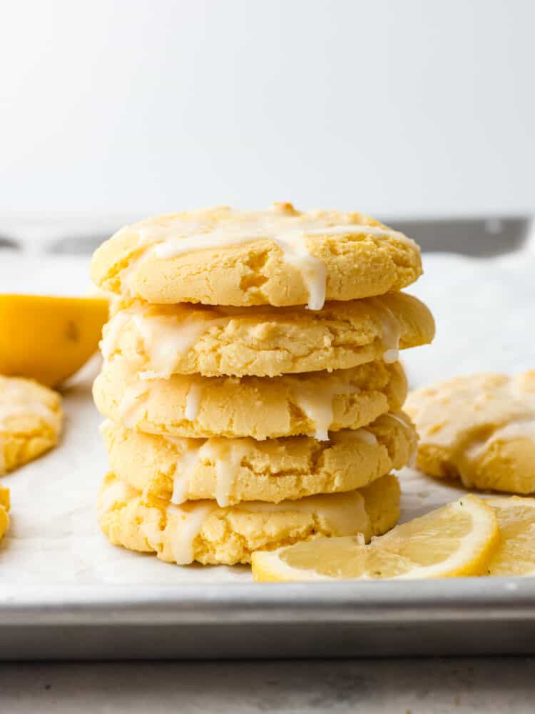 A stack of lemon cake box cookies on a baking sheet with lemon slices. 