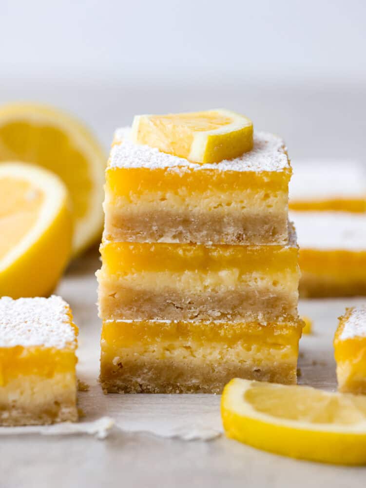 A stack of lemon cheesecake bars with a lemon slice on top. 
