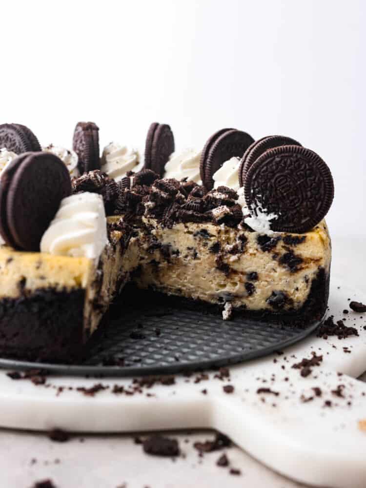 An oreo cheesecake with one slice taken out so that you can see the inside. 