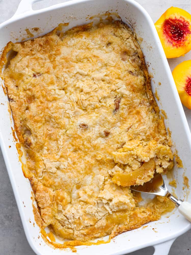 Top-down view of an entire peach dump cake with a scoop taken out of it.