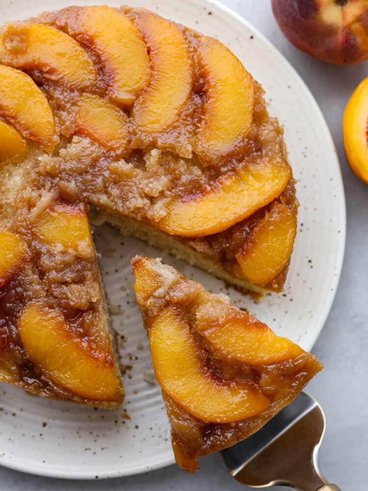 A peach upside down cake with a slice being taken out. 