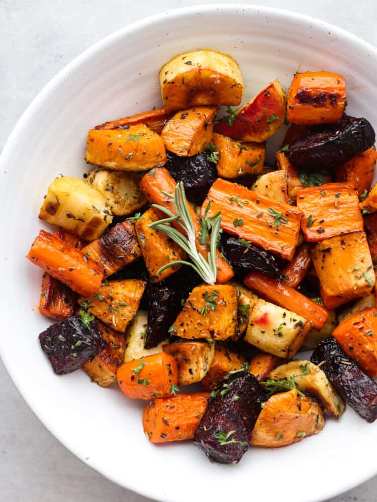 A white bowl filled with roasted root vegetables. 