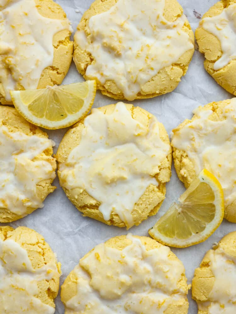 Lemon cookies with a glaze on parchment paper with fresh lemon slices. 