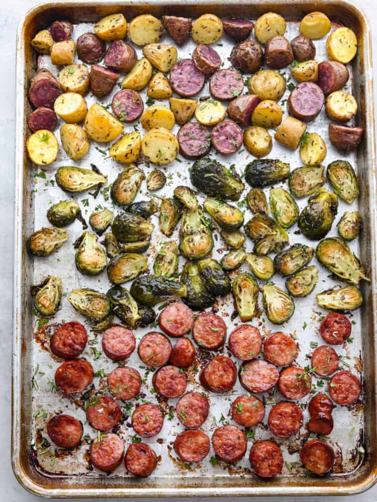 A sheet pan with cooked sausage and veggies on it. 
