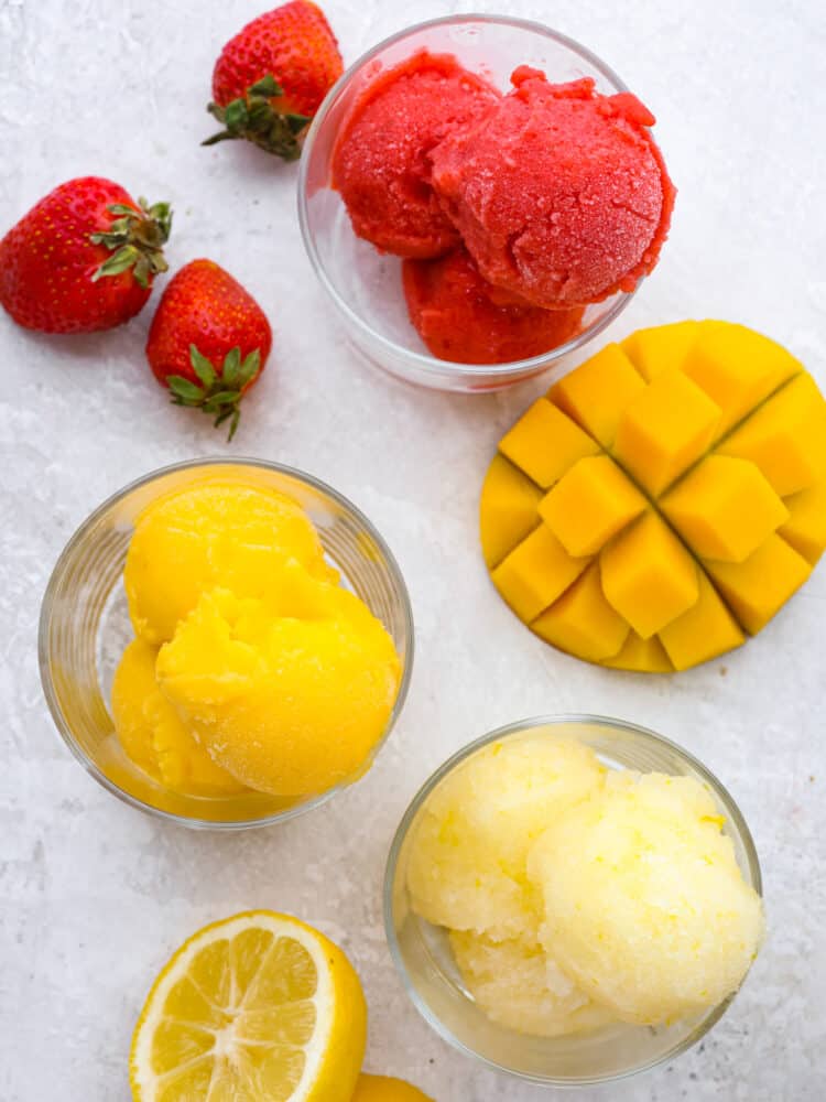 The topview of strawberry sorbet, lemon sorbet and mango sorbet scooped in glass cups. 