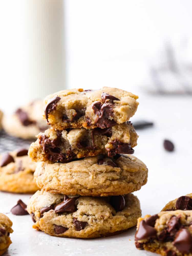 A stack of vegan chocolate chip cookies. The top cookie has a bite taken out of it. 
