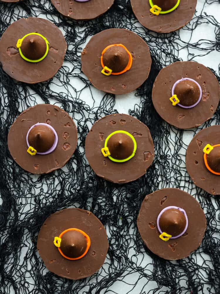 Top-down view of witch hat cookies on top of black netting.