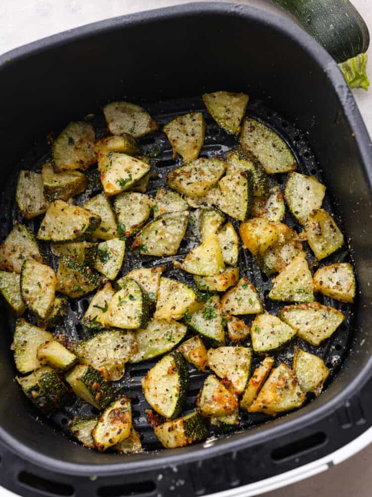 Cooked zucchini bites in an air fryer basket. 