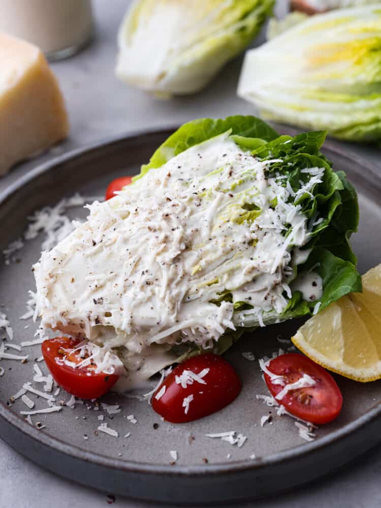 A caesar wedge salad with dressing and cheese on top sitting on a plate