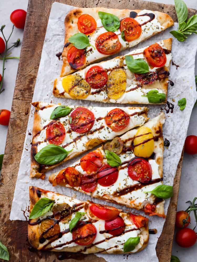 Top-down view of sliced caprese flatbread on parchment paper.