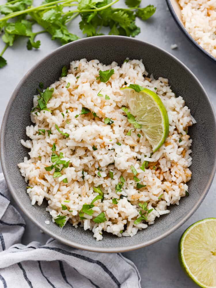 A gray bowl of cilantro lime rice with a lime wedge on top. 