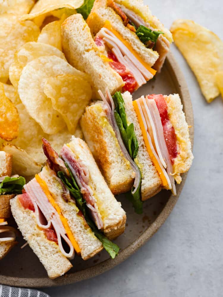 3 club sandwiches served on a plate with potato chips.