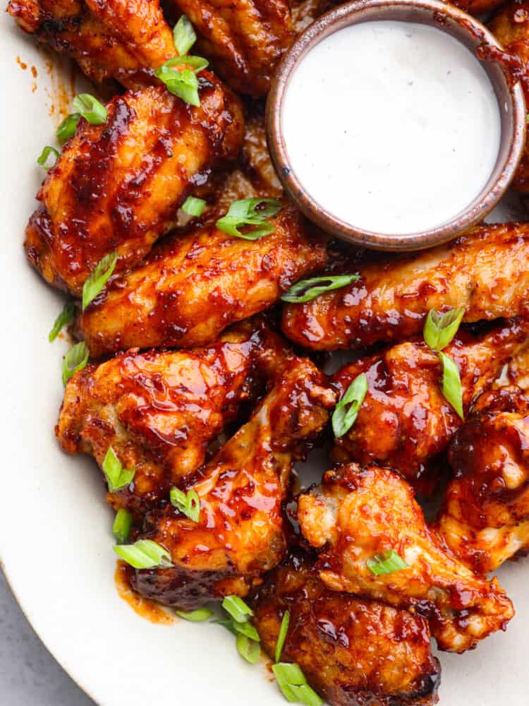 A platter of honey chipotle wings with some ranch dipping sauce. 